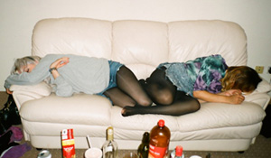 Students passed out on a couch, hungover from binge drinking