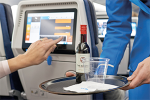 An airline flight attendant serving alcohol to a passenger