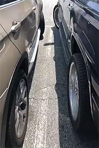 two cars parked too close to each other in a parking lot