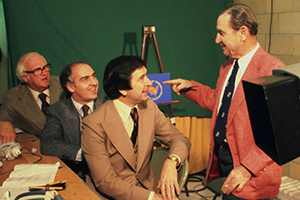(Sitting, left to right) broadcasters Bones McKinney (former Wake Forest basketball coach), Billy Packer (former Wake Forest basketball player/asst. coach), and Jim Thacker (WBTV sports director), with C.D. Chesley (standing), behind the scenes at the 1977 NCAA men's basketball final, North Carolina vs. Marquette, in Atlanta, Georgia.